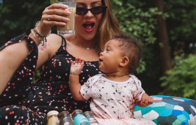 Une maman en train de boire un verre avec son bébé en extérieur