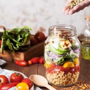 Une salade mélangée avec des graines et du tofu dans un bocal en verre