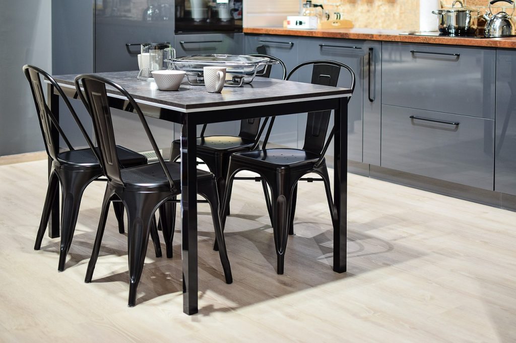 cuisine avec tables et chaises au milieu et vaisselle posée sur la table